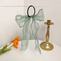 Detail of mint green organza bow hair tie with long ribbons hanging on white background - Blue