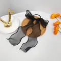 Detail of a black organza bow hair tie with long ribbons on a wooden tray decor - Black