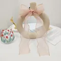 Detail of light pink organza bow hair tie with long ribbons on a beige vase - Pink