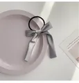 Grey satin bow hair scrunchie with long ribbons on a decorative display plate - Gray