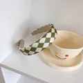 Dettaglio del cerchietto a scacchi verde e beige appoggiato su una tazza smile - Cerchietto Verde