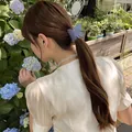 Pinza de pelo mariposa azul mate mostrada en un peinado elegante en ambiente natural - Gris