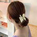 Detail van een matgroene vlinder haarklem gestyled op een lage knot haarkapsel - Beige