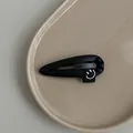 Detailed close-up of a black PU leather droplet hair clip with a cute smiley face tag - Black
