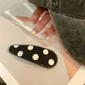 Flat oval hair clip with black and white polka dot pattern on a clean white background - Polka Dot / Teardrop / Black