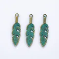 Detailed view of vintage bronze feather pendants with teal blue enamel finish and hole - Antique Green