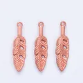 Three rose gold feather pendants with intricate hollow patterns and top rings for DIY - Rose Gold