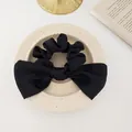 Dettaglio di un elastico in raso nero con fiocco grande su un vassoio in ceramica fine - Nero