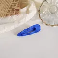 Close-up van de matblauwe haarclip op een esthetische witte papieren achtergrond - Blauw Waterdruppel