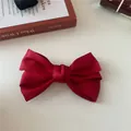 Close-up of a vibrant red satin double-layered bow hair clip with silky smooth texture - Red