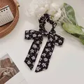 Floral bow scrunchie with long ribbons in black and purple chiffon on soft background - Black