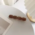 Vue détaillée d'une pince à cheveux en acrylique marbré caramel avec segments résine - Café Foncé