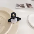 Detalle de pinza para el pelo negra en forma de corazón con acabado nacrado en un plato - Estilo Corazón Negro
