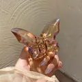 Gros plan d'une petite pince à cheveux papillon avec finition aurore irisée et ressort doré - Thé Irisé