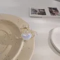 Detalle de una pequeña pinza de pelo en forma de corazón de acrílico con muelle de metal oro - Estilo Corazón Champaña