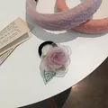 Dettaglio dell'elastico per capelli con fiore di camelia in organza lilla e foglia verde - Elastico per capelli