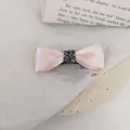 Detail van roze satijnen haarstrik met donkere strass-steentjes en metalen clip - Roze