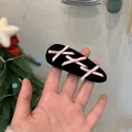 Gros plan sur une pince à cheveux en velours avec des détails de ruban rose - Style Lacets en Satin / Style Nœud Noir Rose