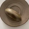 Detalle macro del clip de pelo ovalado ámbar con grabado La France en cuenco cerámico - Café con Leche