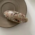 Primer plano de un pasador ovalado vintage con motivos de mármol en plato cerámico - Arcoíris
