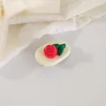 Close-up of a 3D red rose tulip hair clip with green leaves on white textured fabric - Red