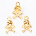 Three gold skull and crossbones metal charms for DIY jewelry making on white background - Gold