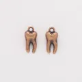 Detailed close-up of antique bronze tooth charms with vintage alloy textures for DIY jewelry - Antique Red Copper