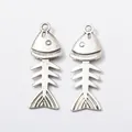 Pair of vintage silver alloy fish bone charms with top hanging loops on white background - Antique Silver