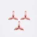 Detailweergave van drie roségouden walvisstaartbedeltjes met ringetjes voor DIY-sieraden - Roségoud