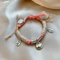 Roze geweven Chinese armband met zilveren gelukshangers en kleurrijke kwastjes - Gelukzak Roze