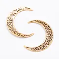 Detailed macro view of vintage crescent moon alloy pendants with hollow filigree patterns - Antique Gold