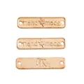 Makro-Detail von roségoldenen Metall-Etiketten mit Handmade- und JK-Gravur für DIY - Handmade Buchstabenschild Stil / KC Gold