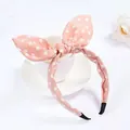 Detailed view of a pink polka dot headband with bunny ears on a white porcelain cup - Pink White Dots
