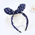 Close-up of cute navy blue polka dot bunny ear headband displayed on a ceramic cup - Navy White Polka Dot