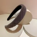 Detail of dark grey quilted velvet headband with sponge padding on white pedestals - Quilted Gray