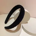 Detail of black quilted velvet headband on white platform showing texture and stitching - Quilted Coffee