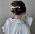 Pale yellow matte hair clip in minimalist hollow design worn on a messy bun hairstyle - Beige