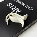 Minimalist cream white wing-shaped ponytail hair clip on a black artistic book - Creamy White (Wing Design)