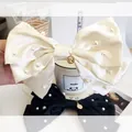 Close-up of cream and black satin bow hair clips with pearls and gold coin pendants - Oversized Pearl Bow Coin Pendant / Off White