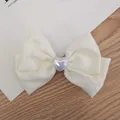 Cream satin bow hair clip with a pearl heart charm on a minimalist background - Satin Bow With Heart Decor / Beige