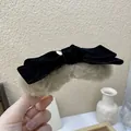 Detail of a velvet bow hair claw clip with beige faux fur texture for women's styling - Camel