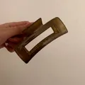 Dettaglio di una molletta per capelli rettangolare color ambra in acrilico lucido - Verde