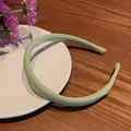 Detail view of light green padded fabric headband with soft texture on wooden background - Green