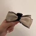 Elegante haarklem met kaki satijnen strik, strass en zwarte rand in de hand - Champagne