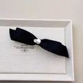 Détail d'un nœud papillon en satin noir avec perle et breloque cœur doré - Noir