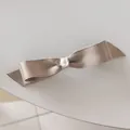 Detalle de lazo de satén champán para el pelo con perla blanca y colgante de corazón - Caqui