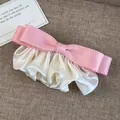 Detalle de pasador de lazo rosa con pliegues de satén crema sobre fondo de lino texturizado - Rosa