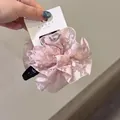 Détail d'un chouchou en dentelle rose avec motifs floraux et étiquette de marque - Pince à cheveux / Rose