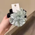 Détail d'un chouchou géant multicouche en dentelle florale et satin soyeux - Cravate à cheveux / Vert