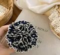 Primer plano de una pinza para el pelo tipo hortensia plisada con flores y encaje - Coletero Azul